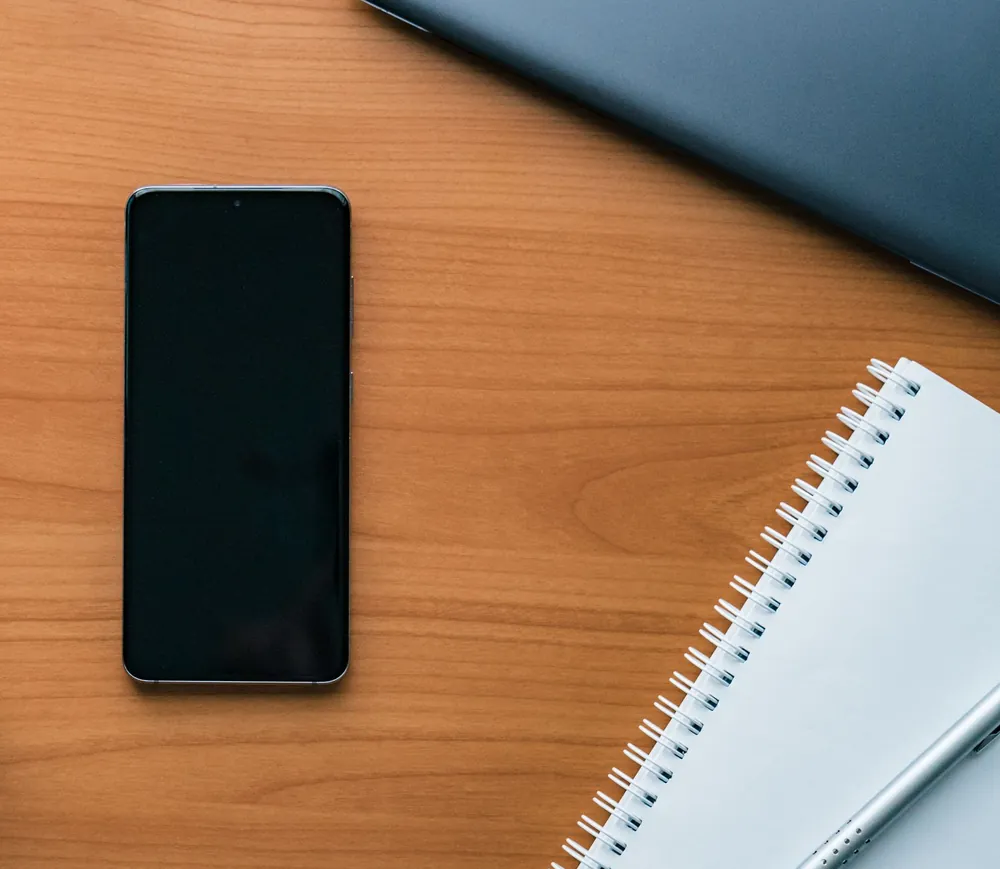 Smartphone and notebook on a wooden desk