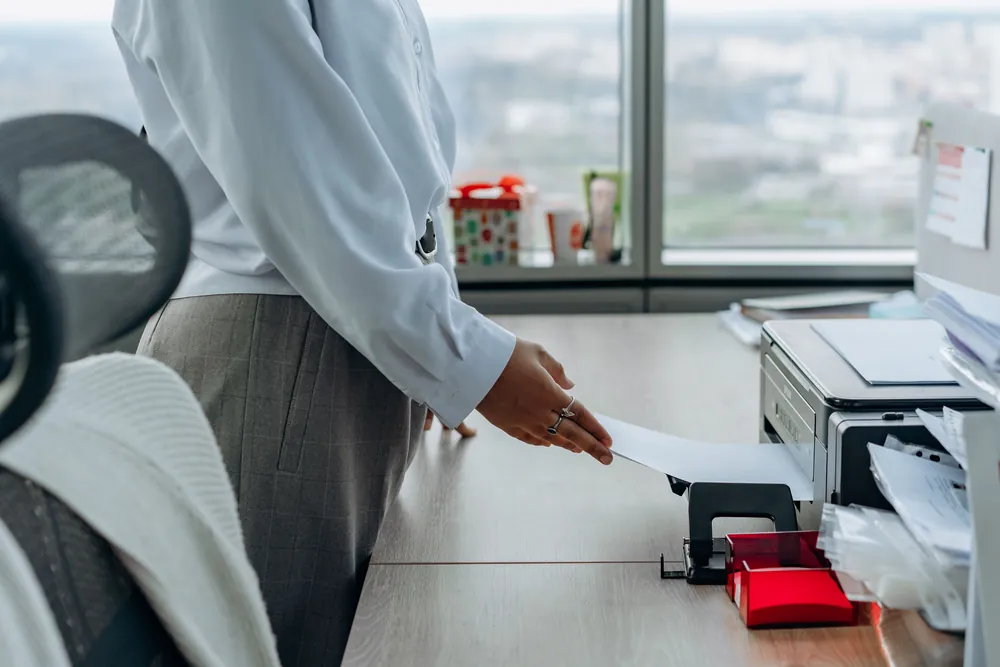 Office printer on a desk with paper